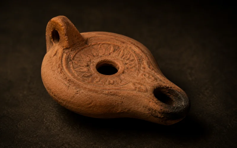 Ancient terracotta oil lamp with molded decoration — illustrative